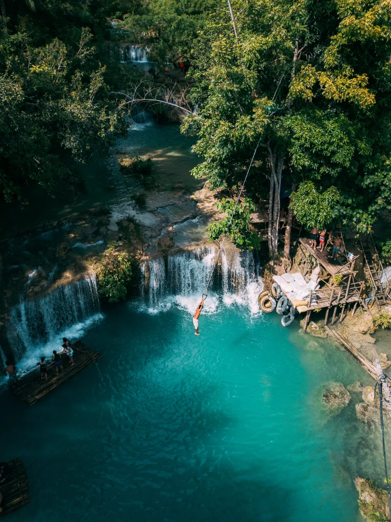 Beautiful Waterfall Streaming Down Into River Surrounded By Greens