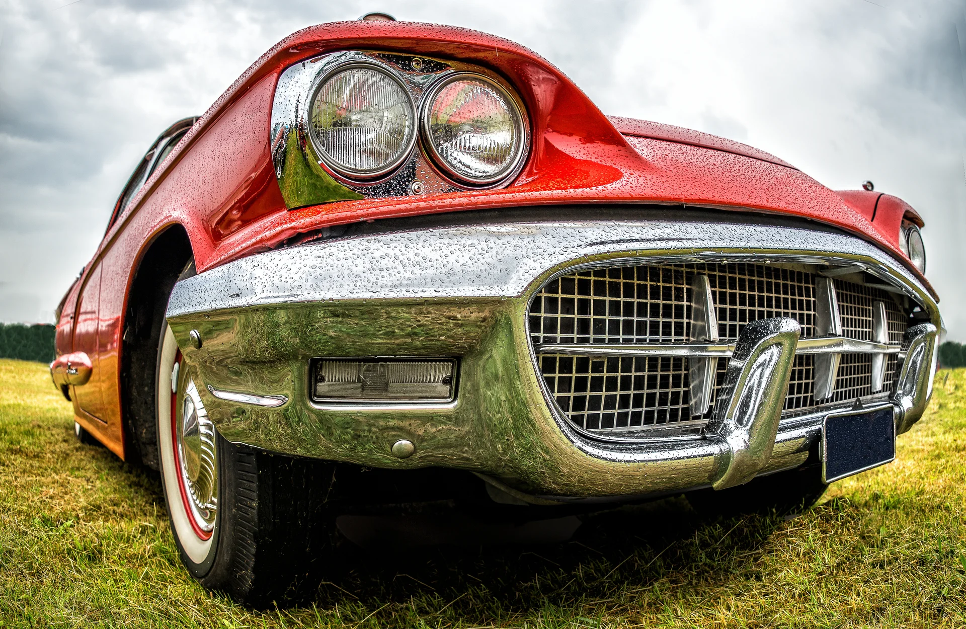 Closeup Shot Front Part Red Car Parked Green Field. Nature wallpaper. 5554×3617px. Free download for personal use.