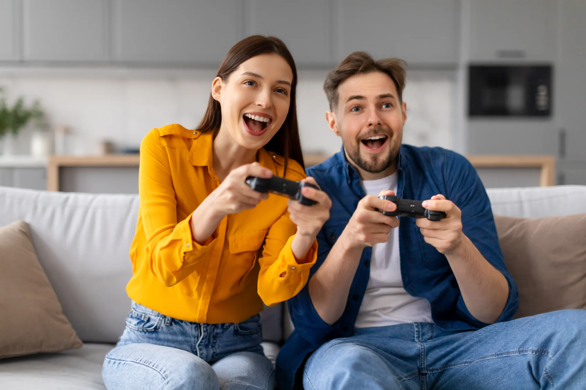 Excited Young Couple Playing Video Games Together Couch. Gaming wallpaper. 6720×4480px. Free download for personal use.