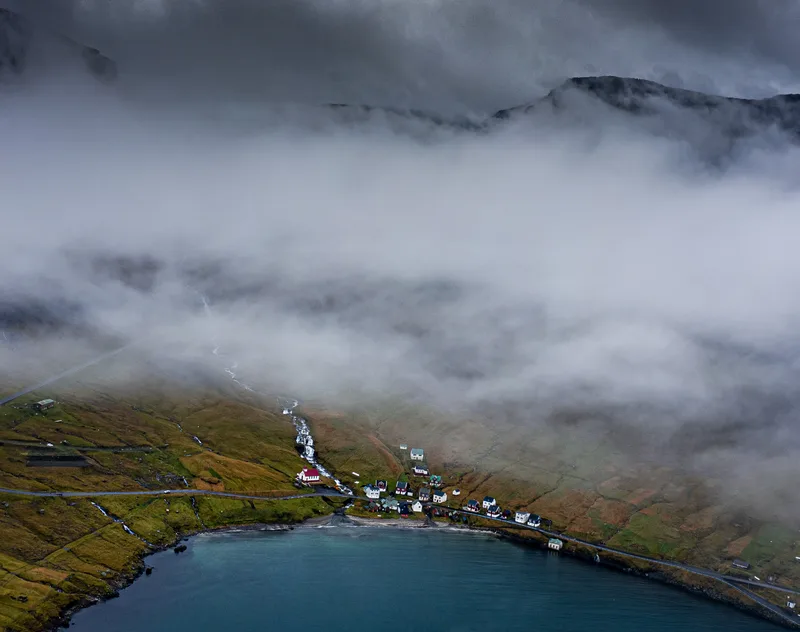 High Angle Shot Houses Grass Covered Hill By Water Captured Foggy Evening