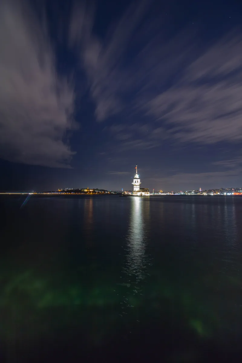 Illuminated City Waterfront Against Cloudy Sky