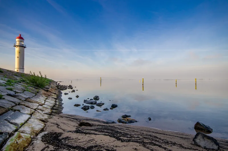 Lighthouse Shore Near Sea With Blue Cloudy Sky
