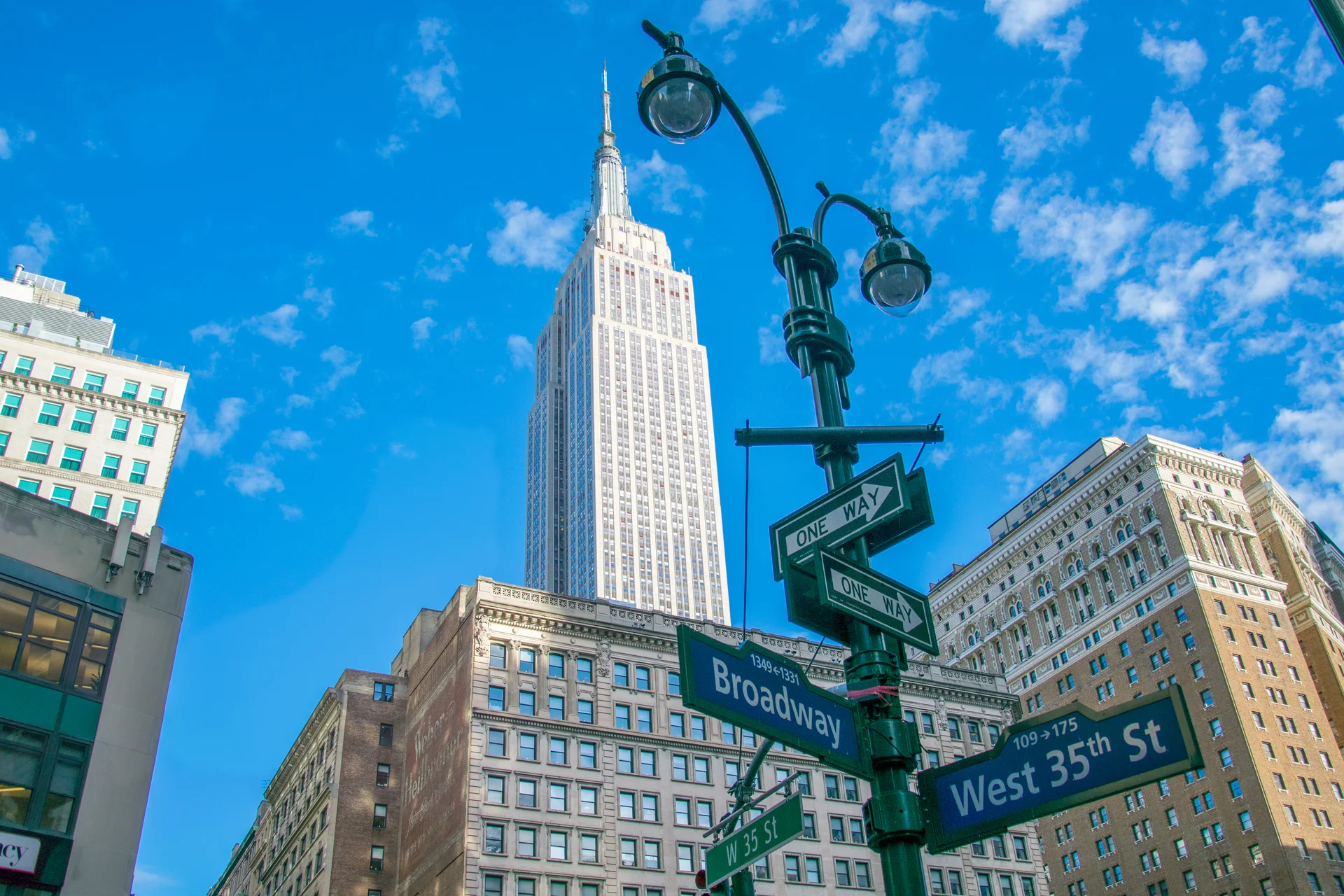 Low Angle View Road Sign Against Empire State Building City. Cities wallpaper. 5540×3693px. Free download for personal use.