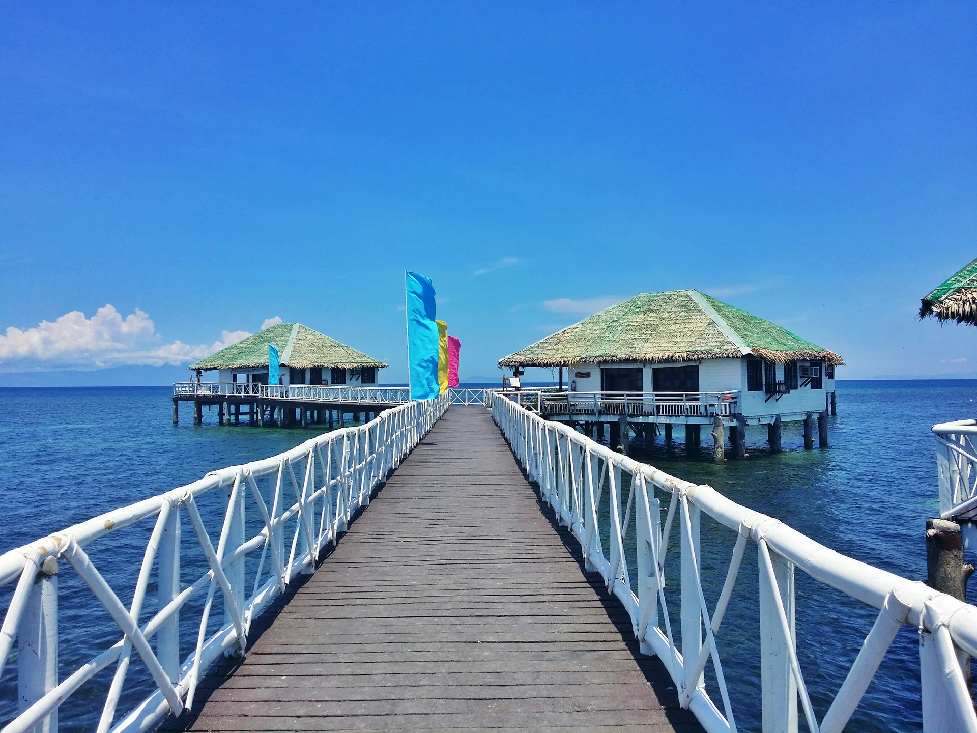 Pier Leading Towards Stilt Houses Sea Against Blue Sky. Nature wallpaper. 4128×3096px. Free download for personal use.