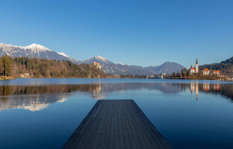 Reflection Mountains Old Buildings Lake With Wooden Pier Foreground