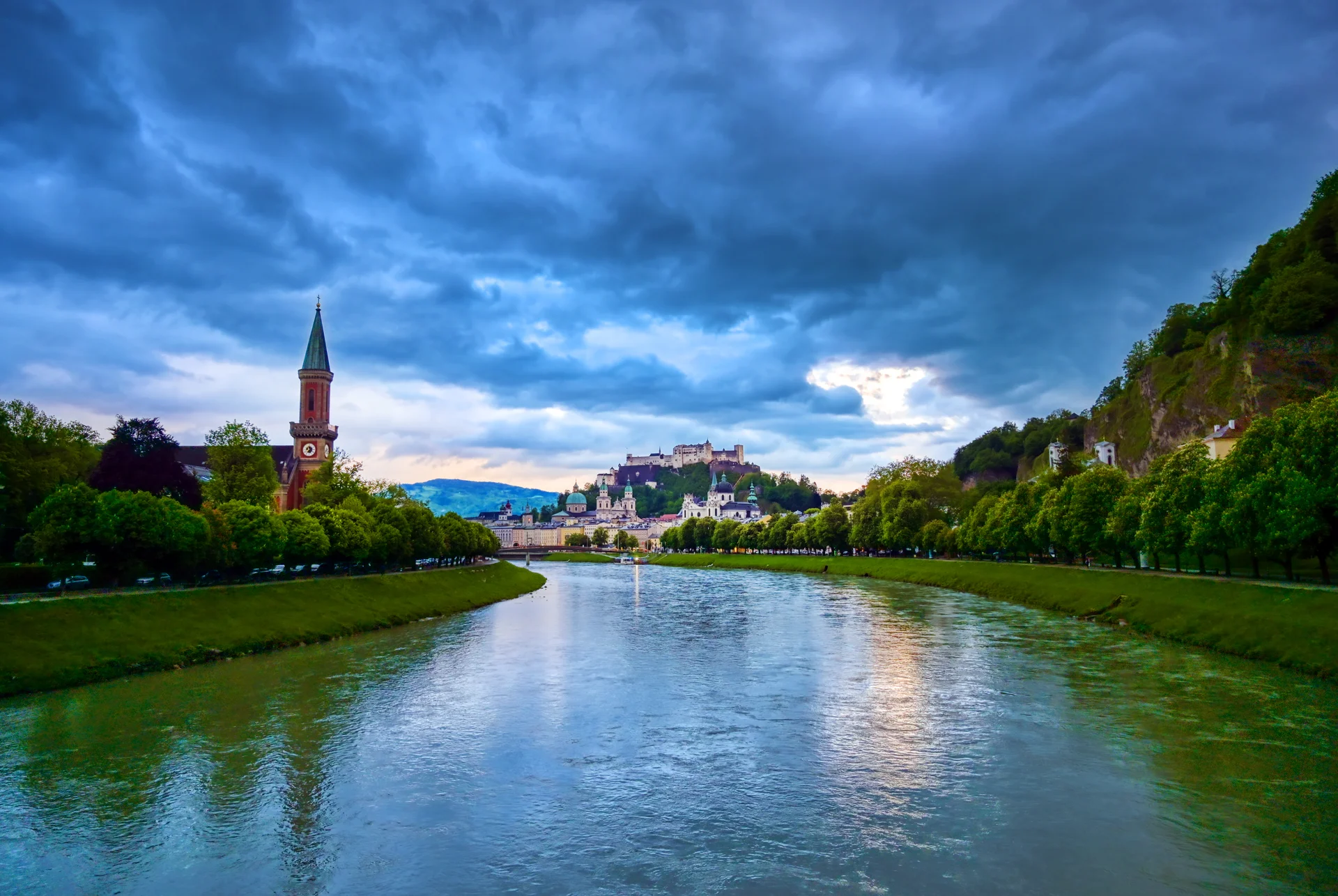 River Amidst Buildings Against Cloudy Sky. Nature wallpaper. 5777×3869px. Free download for personal use.