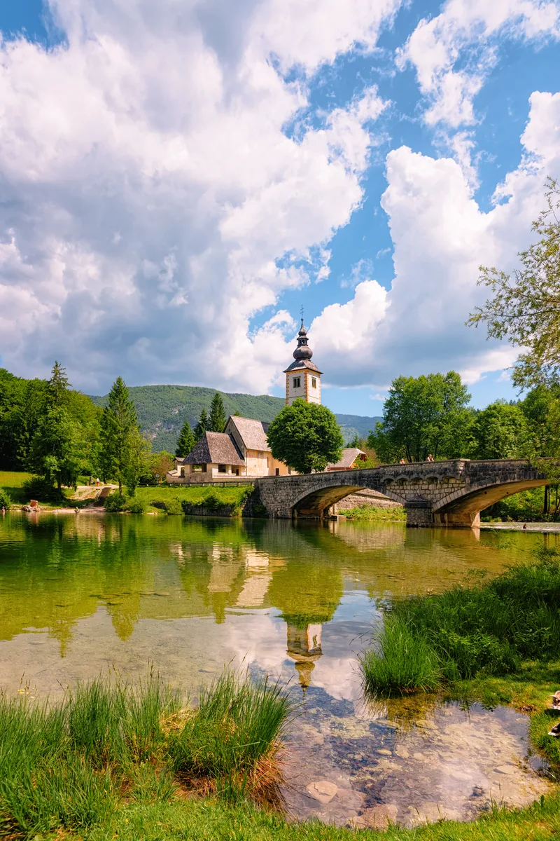 Scenery With Church Saint John Baptist Bohinj Lake Slovenia Nature Slovenija View Blue Sky With Clouds Beautiful Landscape Summer Alpine Travel Destination Julian Alps Mountains