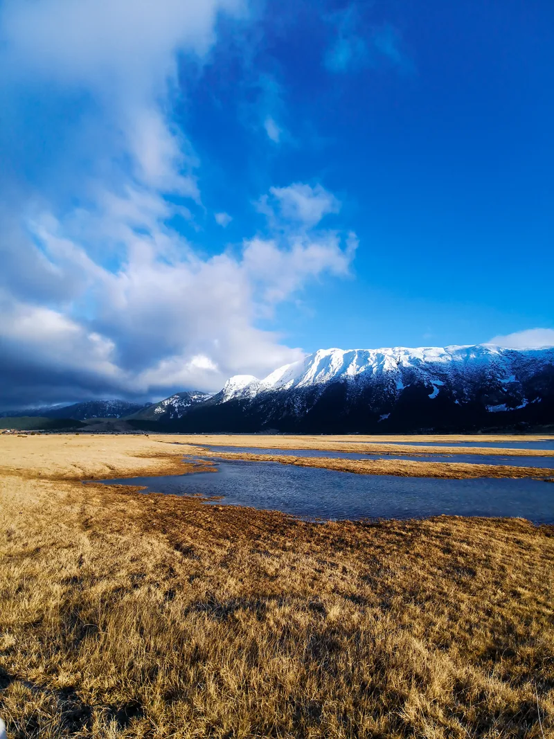 Scenic View Lakeshore Against Snowcapped Mountain Blue Sky