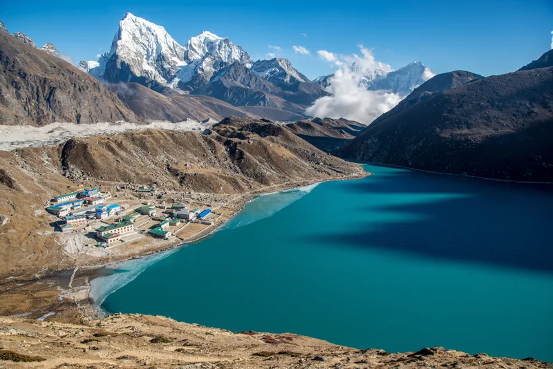 Small Town Near Blue Body Water Surrounded By Beautiful Mountains