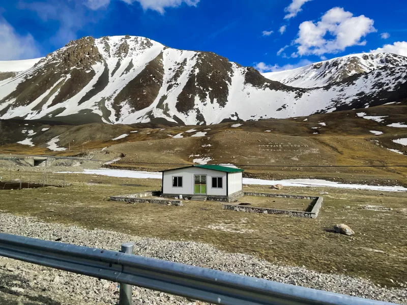 Small White Building With Green Roof Sits Front Mountain