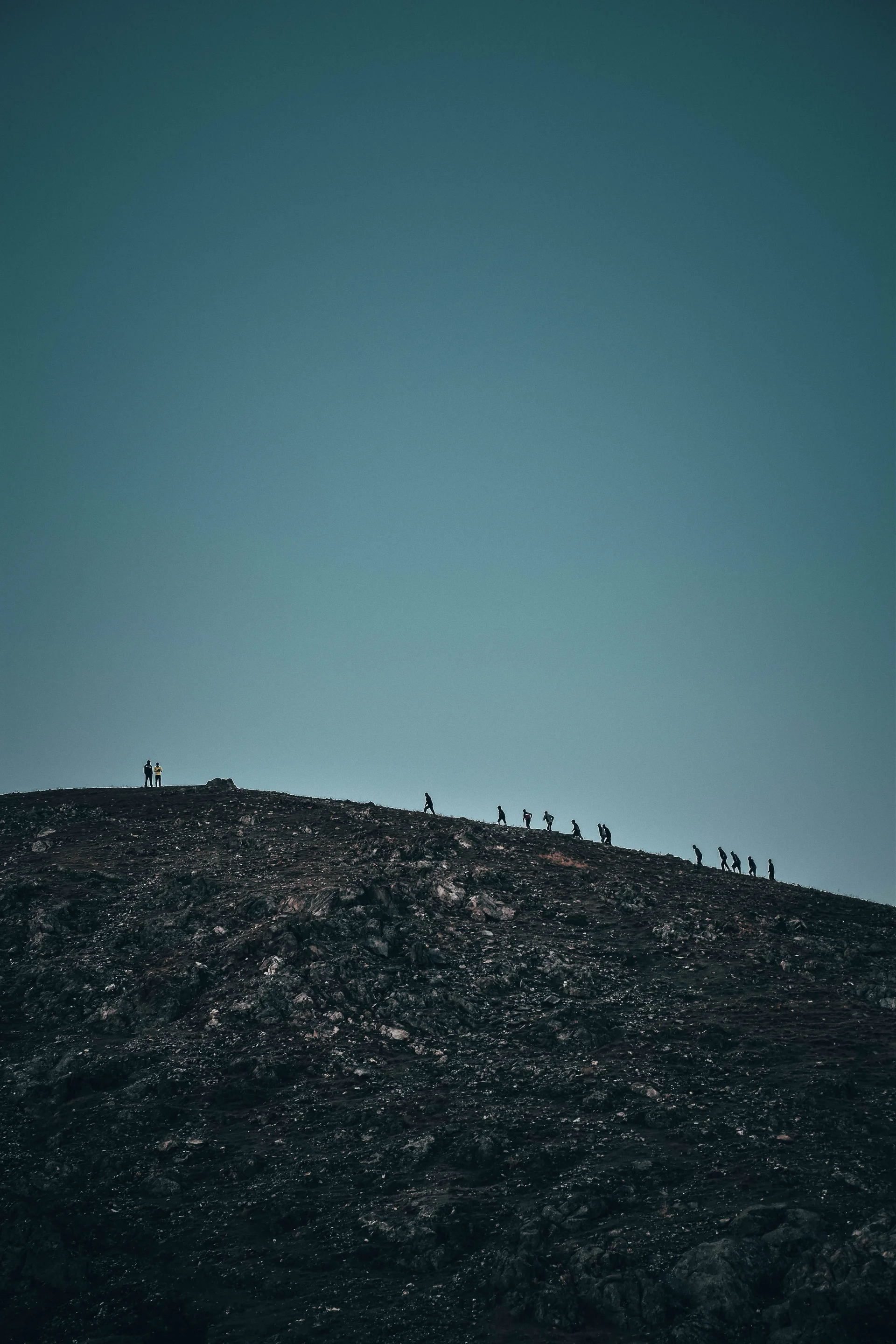 Vertical Shot People Walking Steep Rocky Hill Distance. Nature wallpaper. 4000×6000px. Free download for personal use.