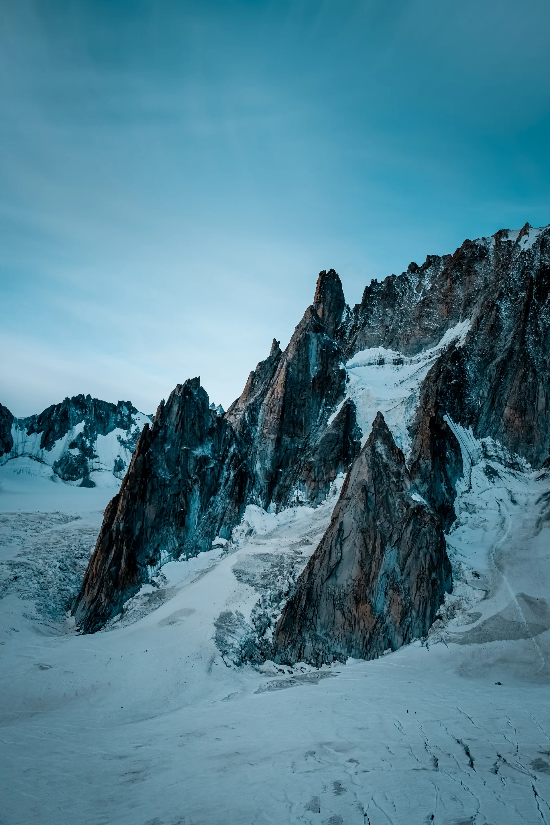 Vertical Shot Snowy Hill Near Mountain Blue Sky. Nature wallpaper. 4000×6000px. Free download for personal use.