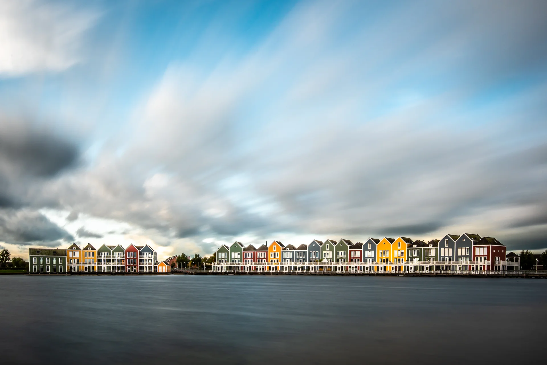 View Buildings By Lake Against Cloudy Sky. Nature wallpaper. 3000×2003px. Free download for personal use.
