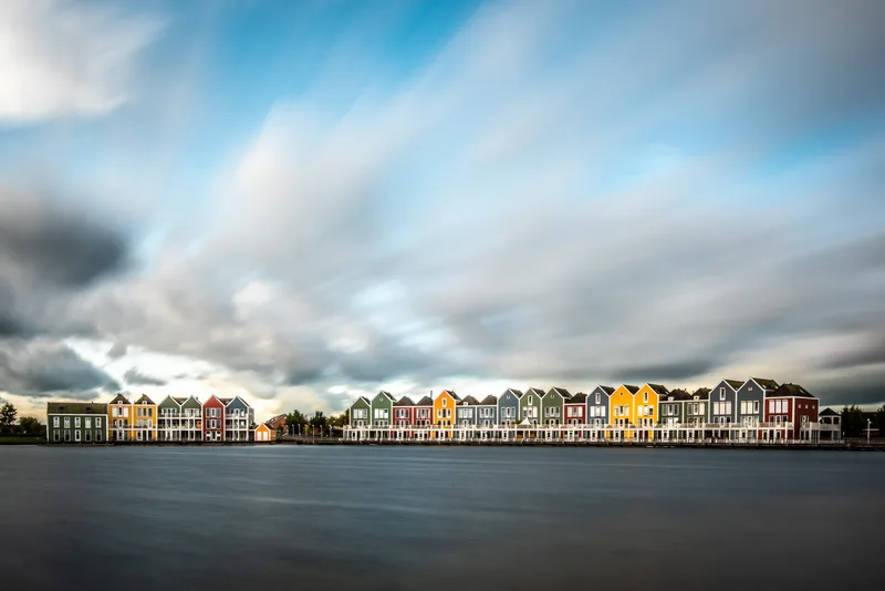 View Buildings By Lake Against Cloudy Sky